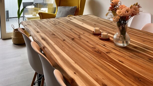 A modern dining area with a wooden table, chairs, and hanging pendant lights.