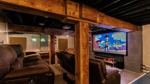 Een gezellig filmtheater met houten balken, comfortabele fauteuils en een groot scherm waarop geanimeerde personages te zien zijn.