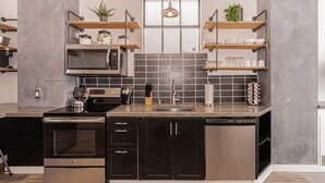 Een moderne keuken met roestvrijstalen apparatuur, zwarte kastjes en houten planken.