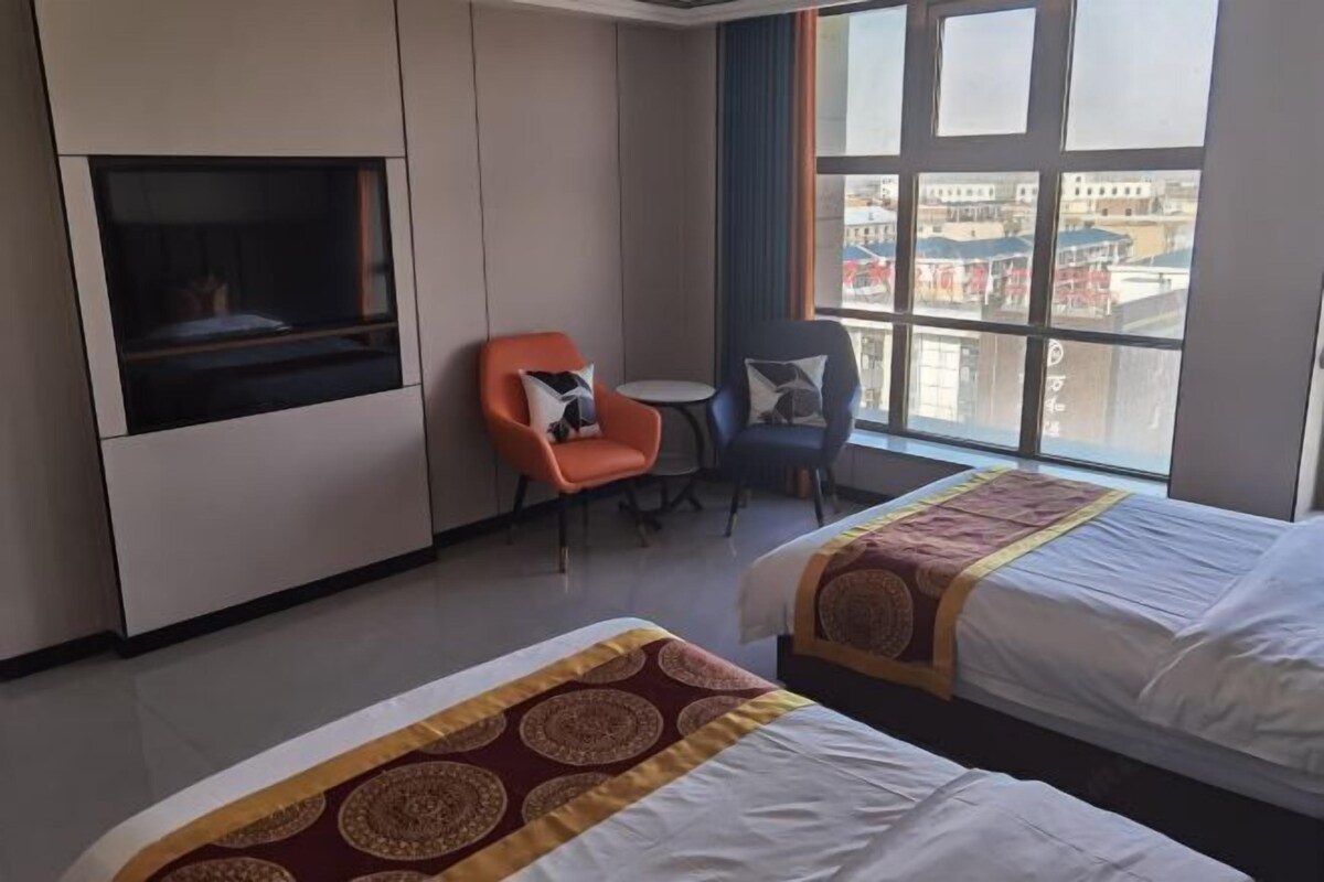 A hotel room with two beds, a TV, a small table, and a chair.