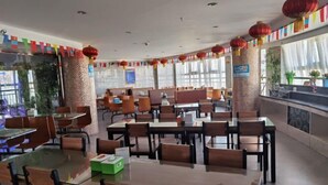 A spacious dining area with multiple tables and chairs, red lanterns, and a view of the outdoors. - Erenhot Hualian International Hotel (Erenhot)
