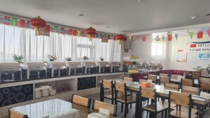 Un comedor con mesas y sillas, una barra de buffet y banderines decorativos.