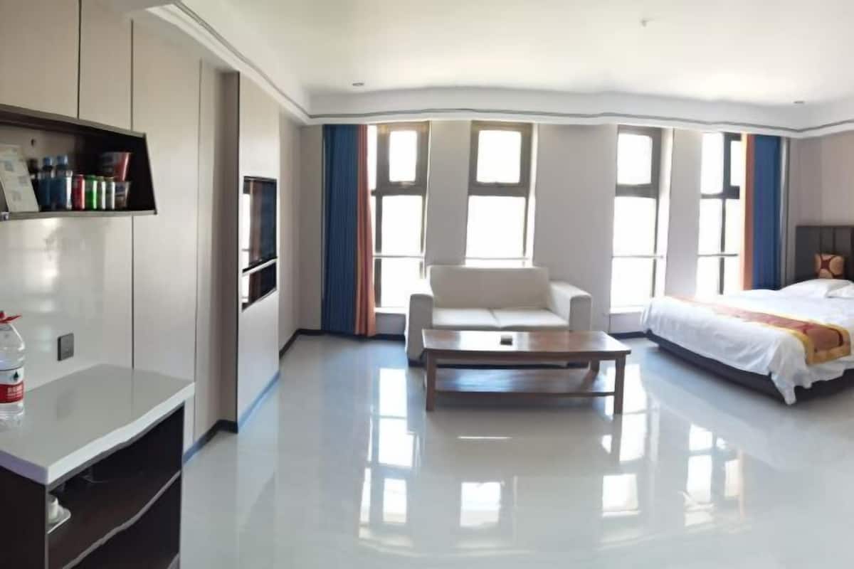 A modern hotel room with a large bed, a sofa, a coffee table, and a TV.