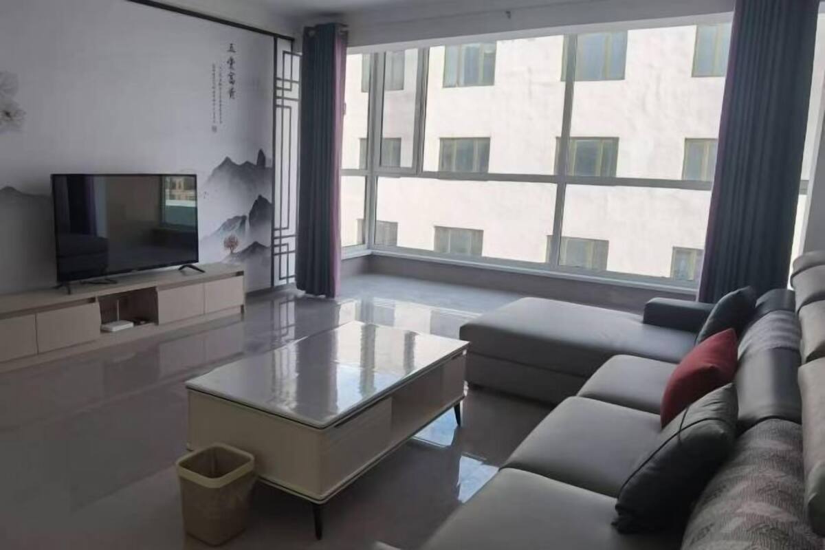 A modern living room with a flat-screen TV, a sofa, and a coffee table.