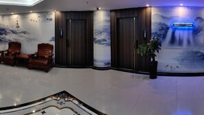 A lobby with a traditional design, featuring wooden chairs, a large mural, and a waterfall display. - Erenhot Hualian International Hotel (Erenhot)
