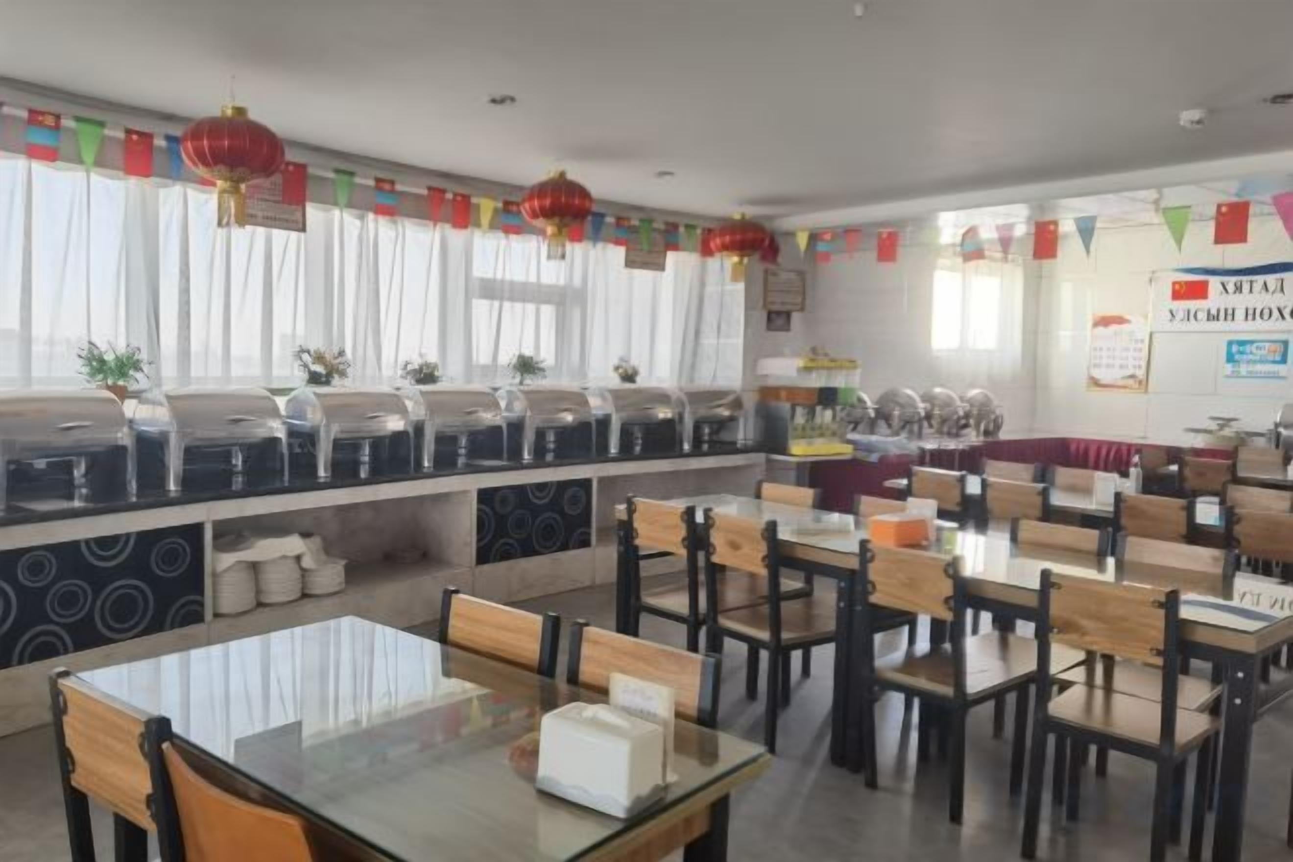A dining area with tables and chairs, a buffet line, and a counter with food items.