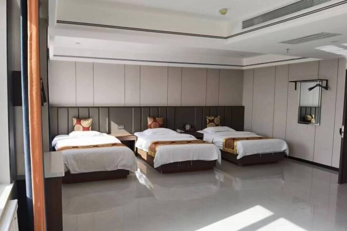 A hotel room with three beds, a large mirror, and a modern design.