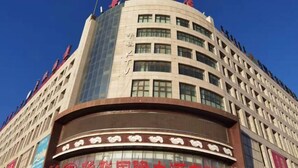 A hotel with a curved facade, multiple floors, and a prominent sign with Chinese characters. - Erenhot Hualian International Hotel (Erenhot)