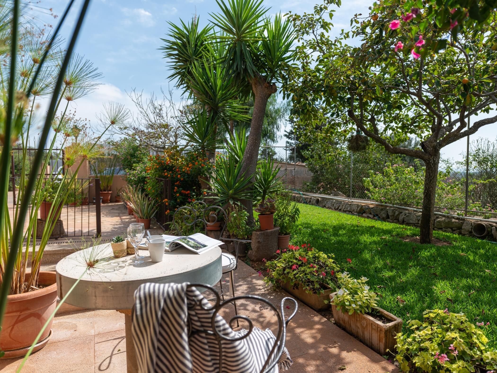 A patio with a round table, chairs, and potted plants.
