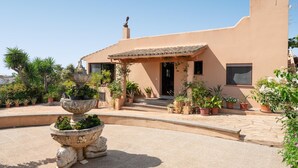 A building with a terracotta facade, a stone fountain, and potted plants in the courtyard.