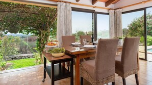 A dining area with a table set for two, large windows, and a view of the outdoors.