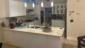 A modern kitchen with white cabinets, a central island, and pendant lighting.