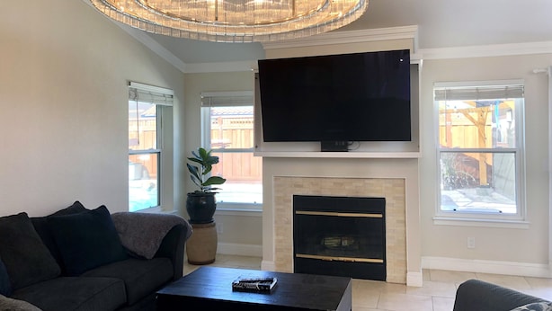 A living room with a large TV, a fireplace, and a chandelier.