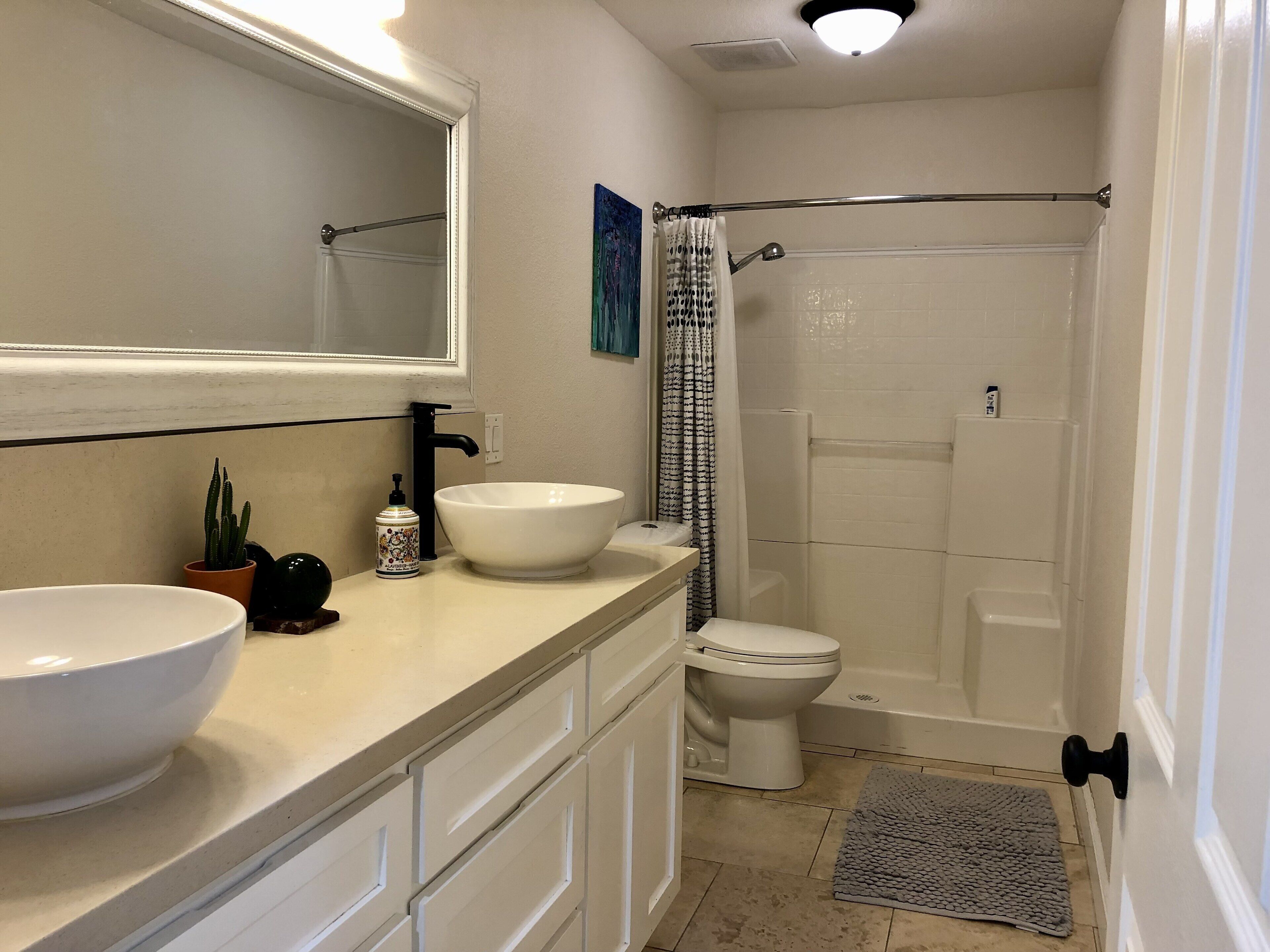 Une salle de bain avec un lavabo blanc, des toilettes, une douche et un miroir.