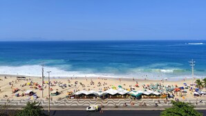 A beach with umbrellas, people, and a clear blue sky. - Ocean View Copacabana Best Spot (Rio de Janeiro)