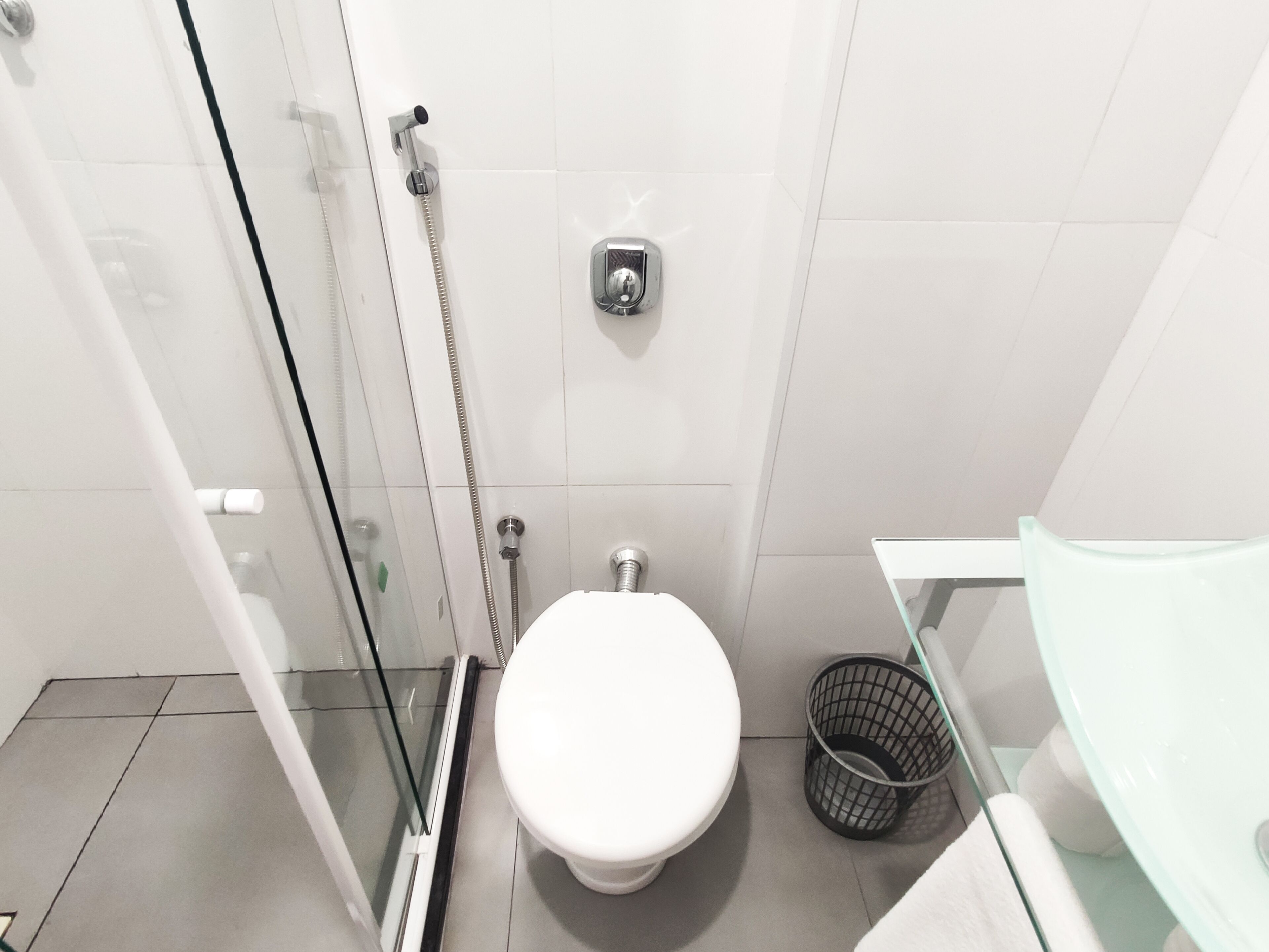 A small, modern bathroom with a glass shower enclosure, a toilet, and a sink with a glass basin.