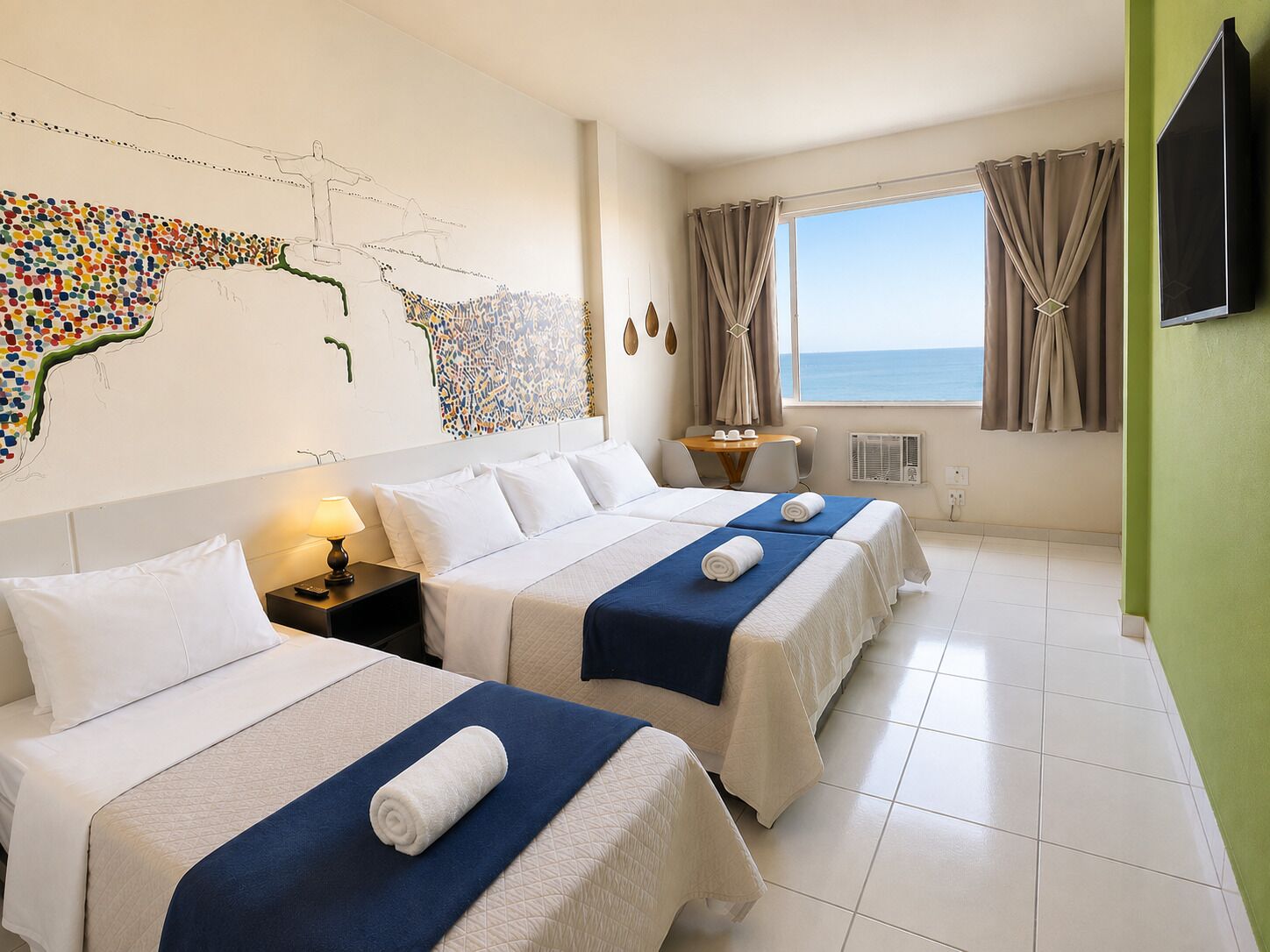 Habitación de hotel con dos camas, un cuadro de un mapa en la pared, televisión y vista al mar.
