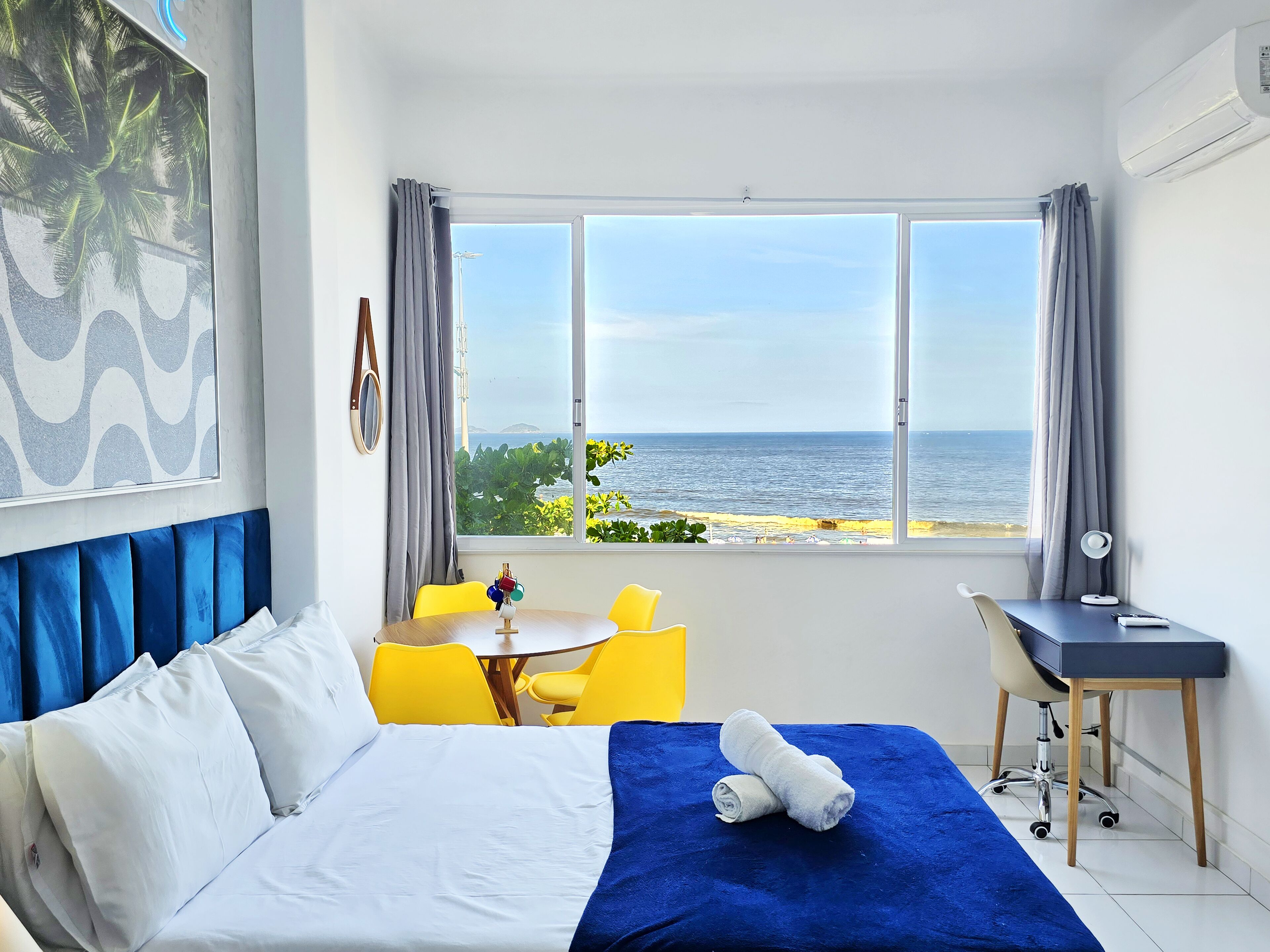 Une chambre d’hôtel avec un lit, un bureau, une chaise et une vue sur la mer.