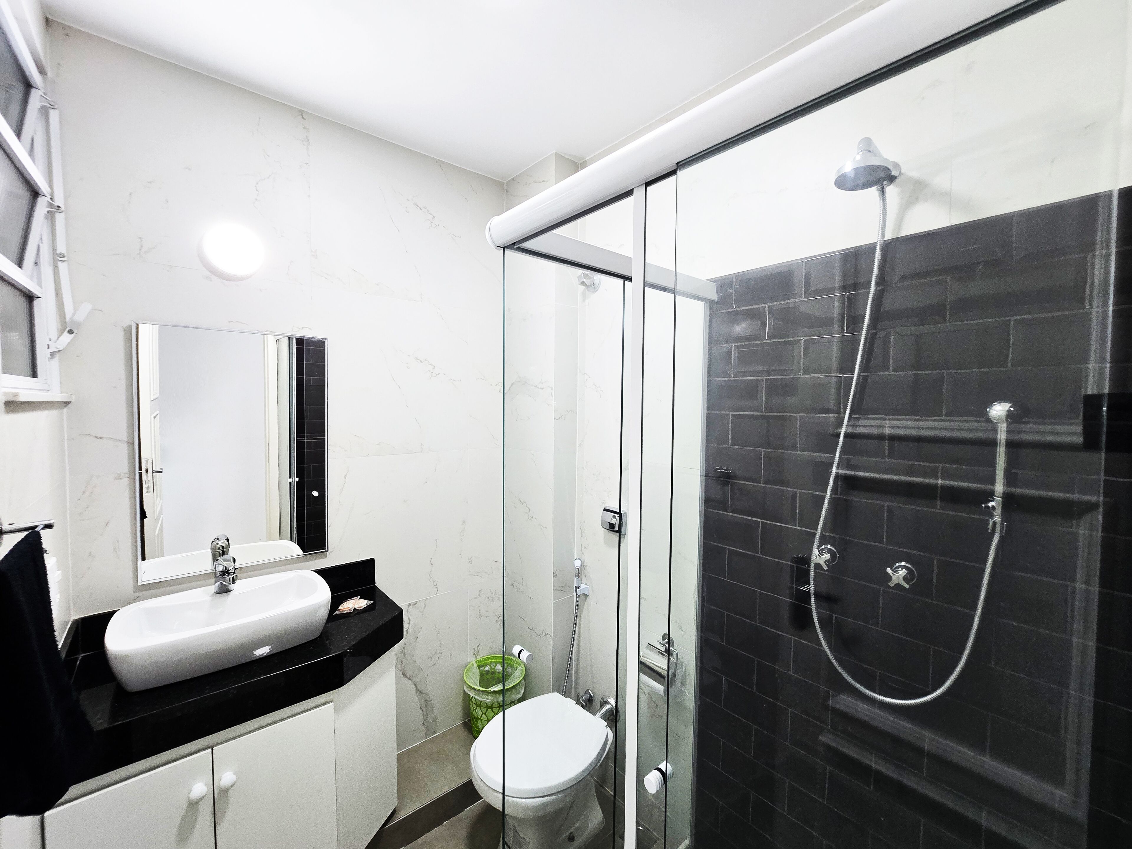 Une salle de bain moderne avec une douche à parois de verre, un lavabo blanc et des toilettes.