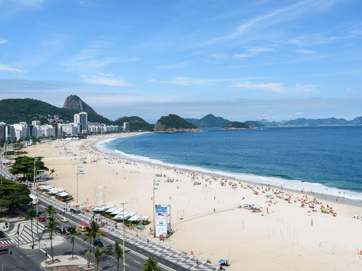 Une plage avec une vue sur la ville en arrière-plan, comprenant une montagne imposante et des bâtiments.