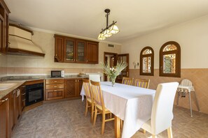 A kitchen with wooden cabinets, a microwave, a dining table with chairs, and a chandelier. - Quiet villa with 4 bedrooms, 2 bathrooms, barbecue, wifi and pool (Inca)