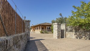 A courtyard with a stone wall, a wooden fence, and a building with a tiled roof. - Quiet villa with 4 bedrooms, 2 bathrooms, barbecue, wifi and pool (Inca)