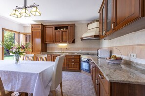 A kitchen with wooden cabinets, a dining table with chairs, a chandelier, and a microwave. - Quiet villa with 4 bedrooms, 2 bathrooms, barbecue, wifi and pool (Inca)