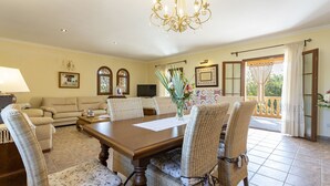 A dining area with a wooden table and wicker chairs, a chandelier, and a balcony with curtains. - Quiet villa with 4 bedrooms, 2 bathrooms, barbecue, wifi and pool (Inca)