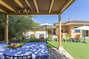 An outdoor patio with a table set for dining, surrounded by chairs and umbrellas, overlooking a swimming pool and a garden. - Quiet villa with 4 bedrooms, 2 bathrooms, barbecue, wifi and pool (Inca)