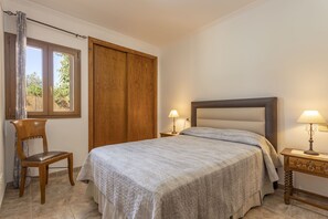 A bedroom with a bed, a wooden chair, a nightstand with a lamp, and a wardrobe. - Quiet villa with 4 bedrooms, 2 bathrooms, barbecue, wifi and pool (Inca)