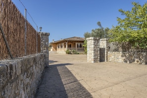 A courtyard with a stone wall, a wooden fence, and a building with a tiled roof. - Quiet villa with 4 bedrooms, 2 bathrooms, barbecue, wifi and pool (Inca)