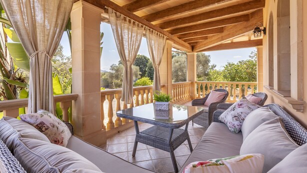 A covered outdoor seating area with wicker furniture, a glass table, and a view of greenery. - Quiet villa with 4 bedrooms, 2 bathrooms, barbecue, wifi and pool (Inca)