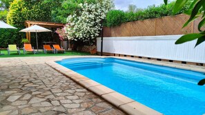 A swimming pool with stone tiles, surrounded by a wooden fence and a white wall. - Quiet villa with 4 bedrooms, 2 bathrooms, barbecue, wifi and pool (Inca)