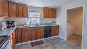 A kitchen with wooden cabinets, a dishwasher, and a coffee maker. - Simba’s House Mid 1800’s Burton Village Retreat (Burton)