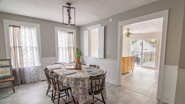 A dining area with a round table, chairs, and a chandelier. There is a view of the outside through a doorway. - Simba’s House Mid 1800’s Burton Village Retreat (Burton)