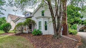 A two-story house with a large front yard, a tree, and a driveway. - Simba’s House Mid 1800’s Burton Village Retreat (Burton)