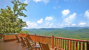 A wooden deck with outdoor seating and a hot tub overlooking a mountainous landscape. - Above It All #38 (Sevierville)