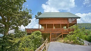 A wooden cabin with a balcony, situated on a hillside with a view of the surrounding landscape. - Above It All #38 (Sevierville)
