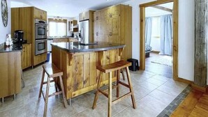 Eine moderne Küche mit Holzschränken, einer Mittelinsel und zwei Barhocker.