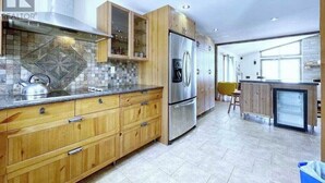 Eine moderne Küche mit Holzschränken, einem Edelstahlkühlschrank und einer gefliesten Spritzschutzwand.