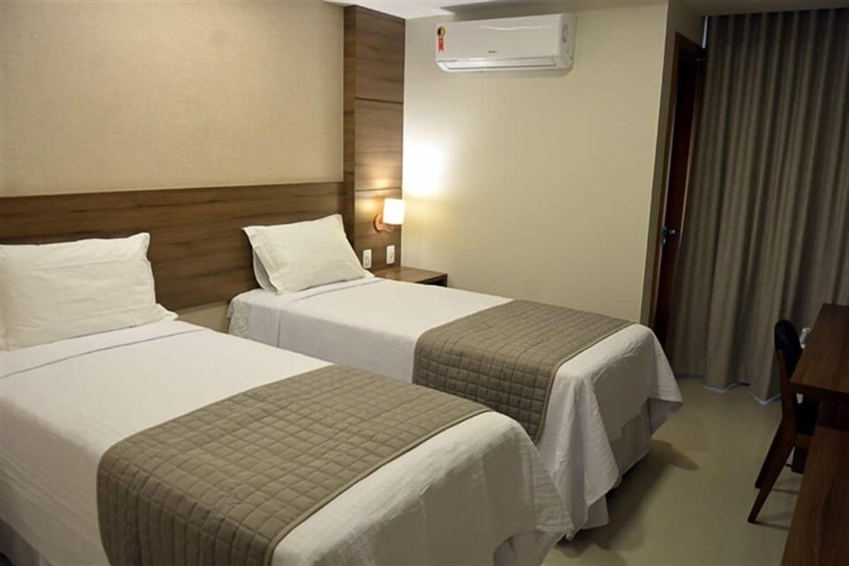 Habitación de hotel con dos camas, un escritorio y una silla.