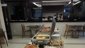 A buffet setup with various food items and plates arranged on a table. - Pituba Praiamar Hotel (Salvador)