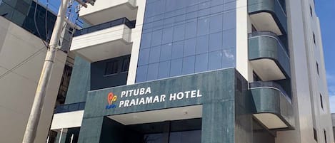 Un moderno edificio de hotel con una entrada destacada, varios pisos y una escalera que conduce a la entrada.