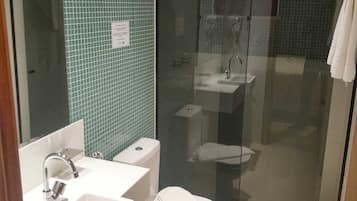 A bathroom with a glass-enclosed shower, a white sink, and a toilet.