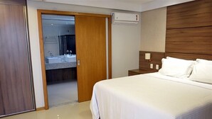 A hotel room with a bed, a wooden headboard, a nightstand, and a bathroom visible through an open door. - Pituba Praiamar Hotel (Salvador)