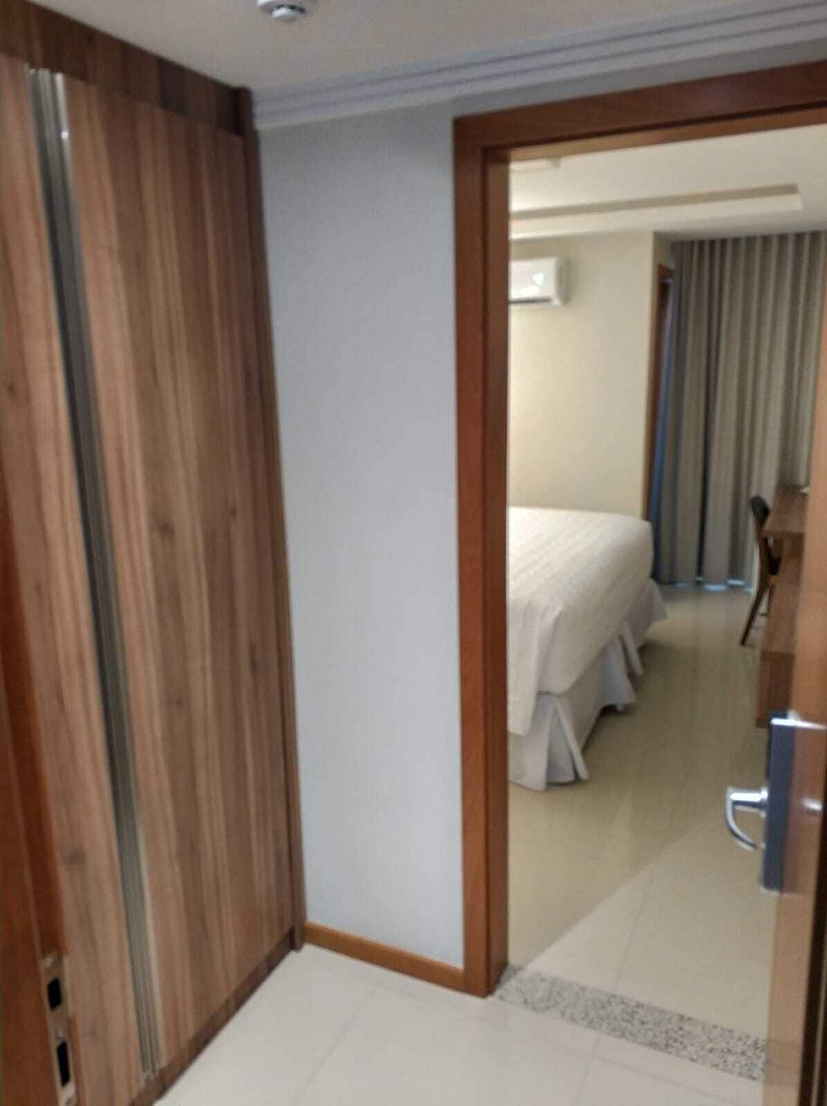 Habitació d'hotel amb un armari de fusta, un llit amb roba de llit blanca i una petita taula amb una cadira.