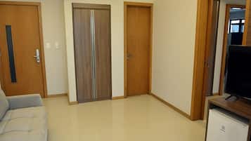 Een kamer met een bank, een televisie op een standaard, en twee houten deuren.