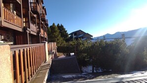 A multi-story building with balconies, a sloped roof, and a view of a lake and mountains in the background.