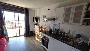 A modern kitchen with a flat-screen TV, wooden chairs, and a dining area with a view of the outside.