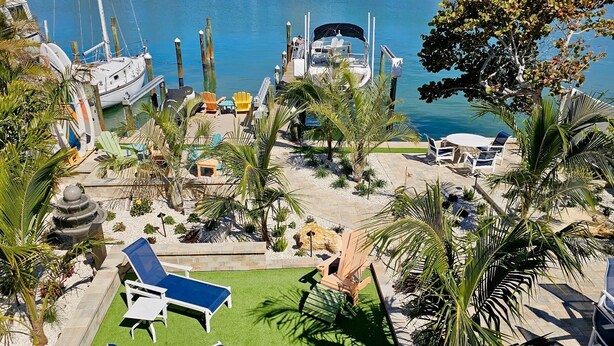 Un puerto deportivo con barcos amarrados, sillas de descanso y una fuente.